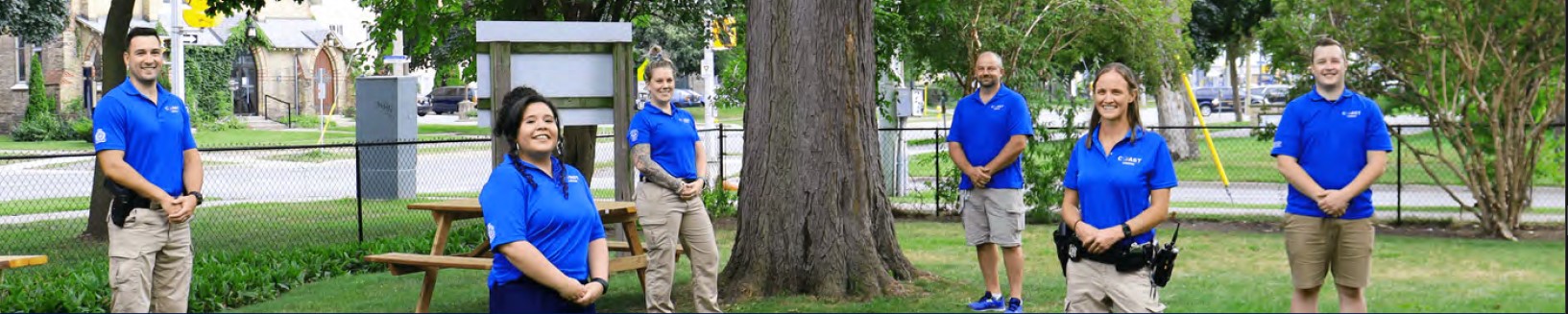 Group image of Coast team members standing in outside in front of a large tree, all wearing blue coast shirts