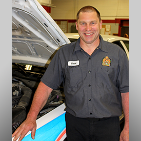 smiling Civilian employee mechanic standing beside police cruiser with it's hood up