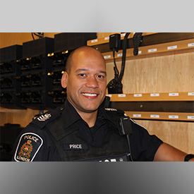 Sergeant Price standing in front of rack of police radios