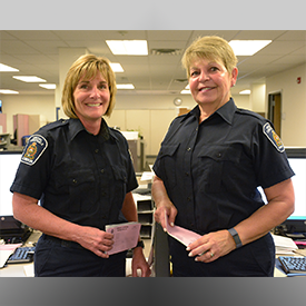 two female special constables, smiling, standing in office