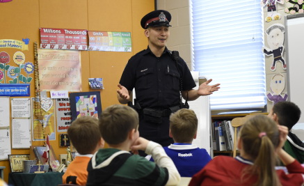 an officer teaches a class of school children