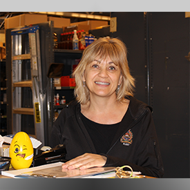 Smiling Civilian employee standing behind desk in storage area